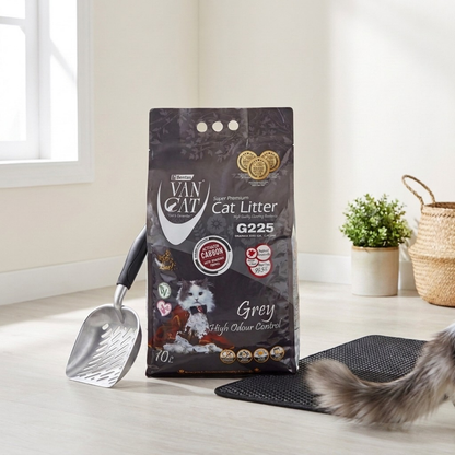 Bag of Van Cat cat litter with a scoop mat and cat tail on a wooden floor.